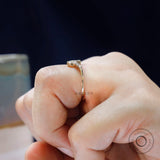 Delicate marquise moissanite V band shown between fingers for scale
