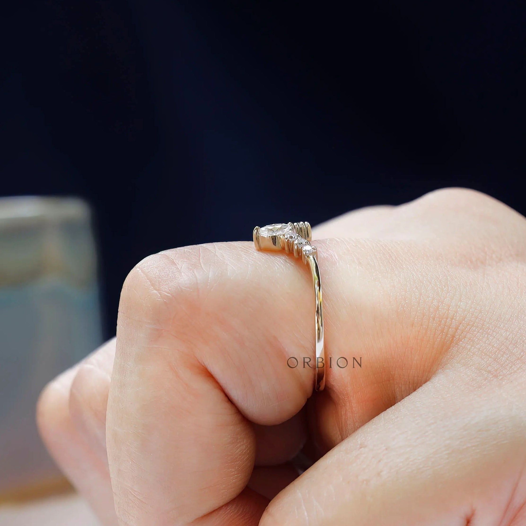Delicate marquise moissanite V band shown between fingers for scale