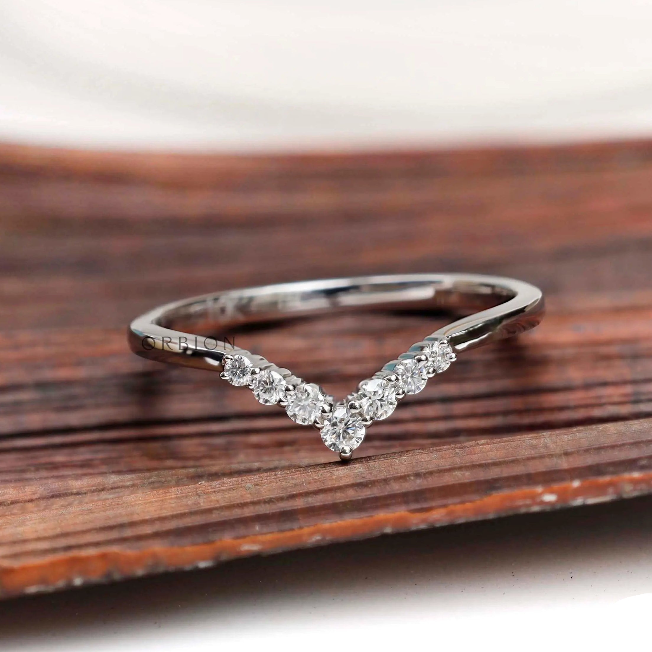 Front view of chevron moissanite wedding band on wooden surface