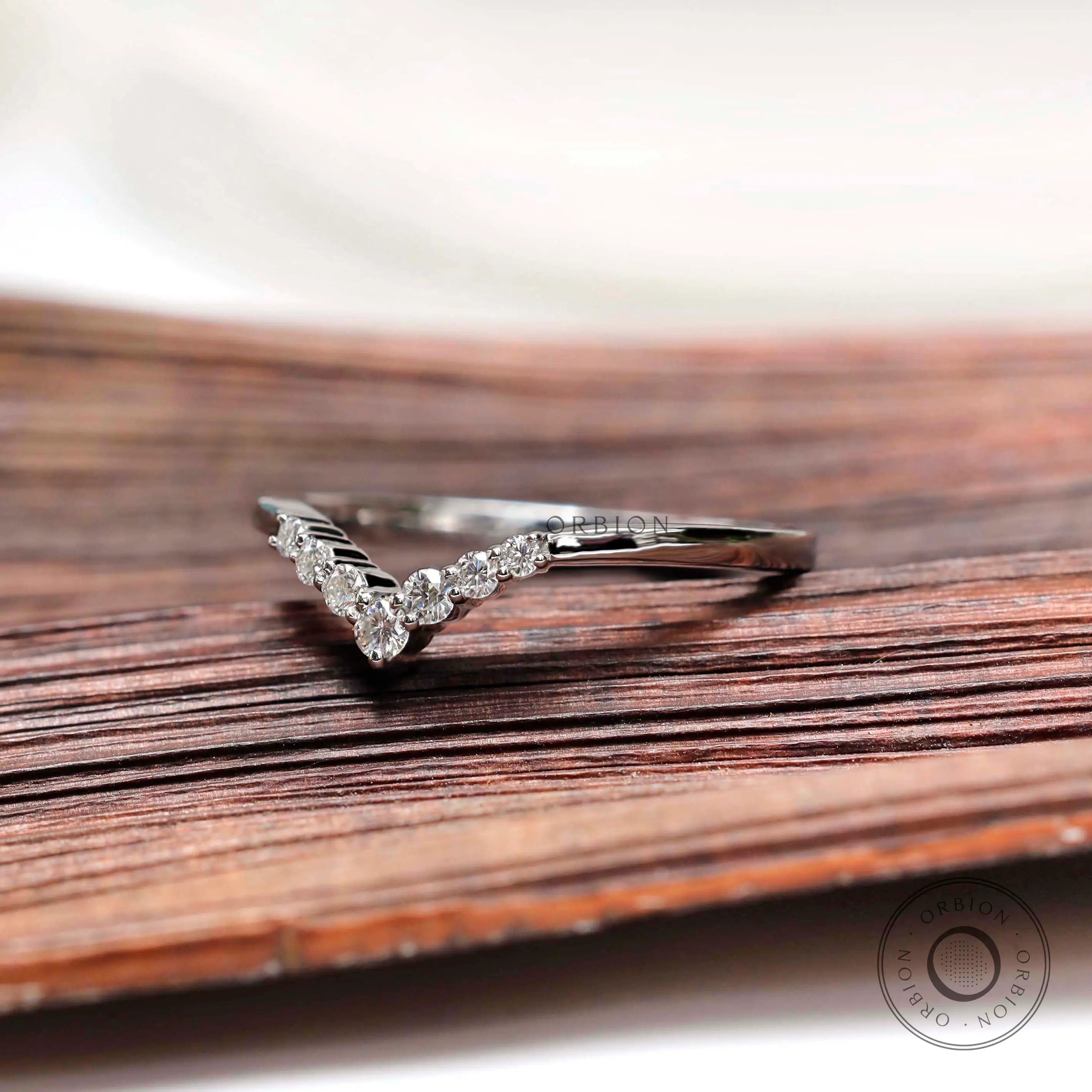 Angled front view of slim chevron moissanite band in white gold