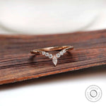 Front view of chevron moissanite wedding band on wooden surface