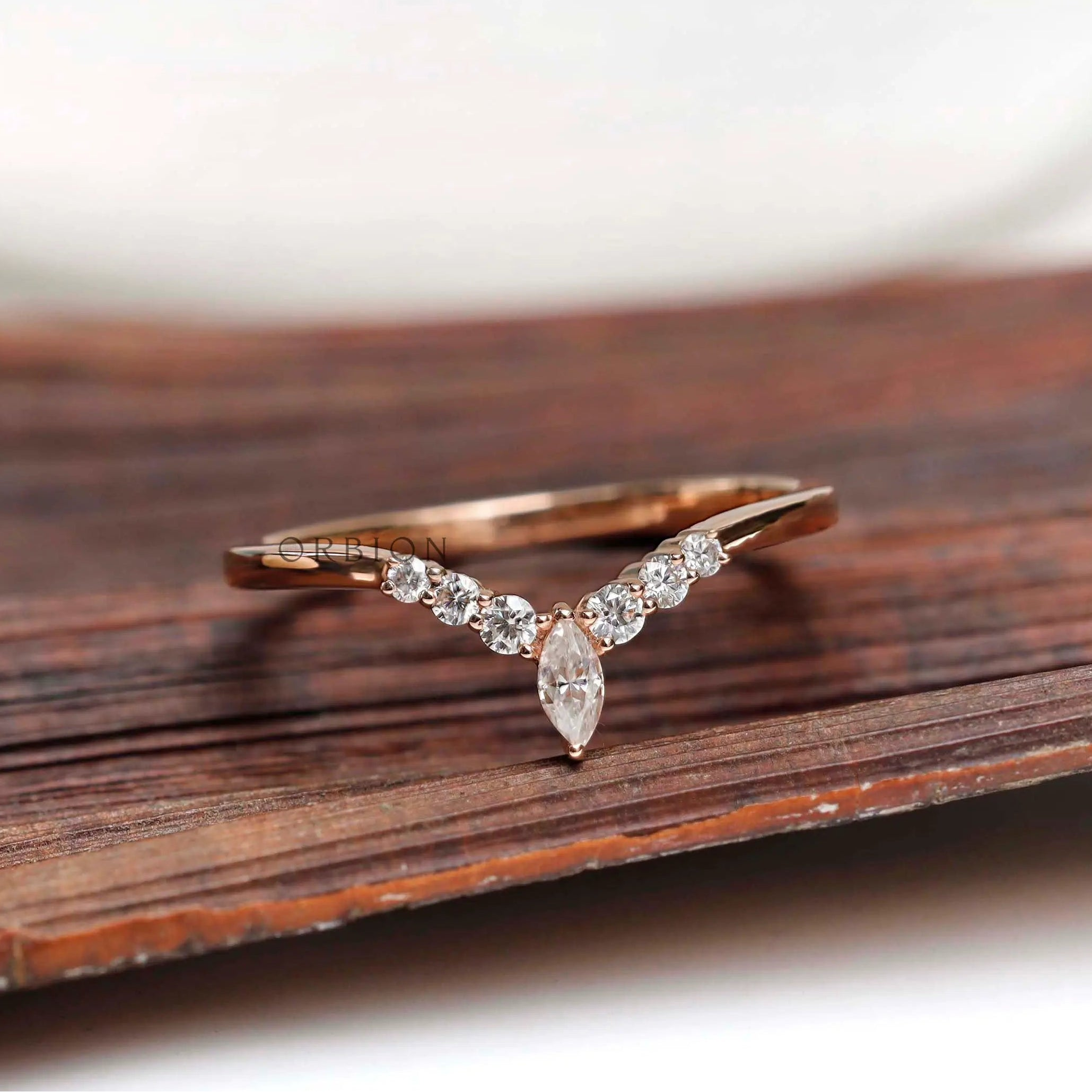 Front view of chevron moissanite wedding band on wooden surface