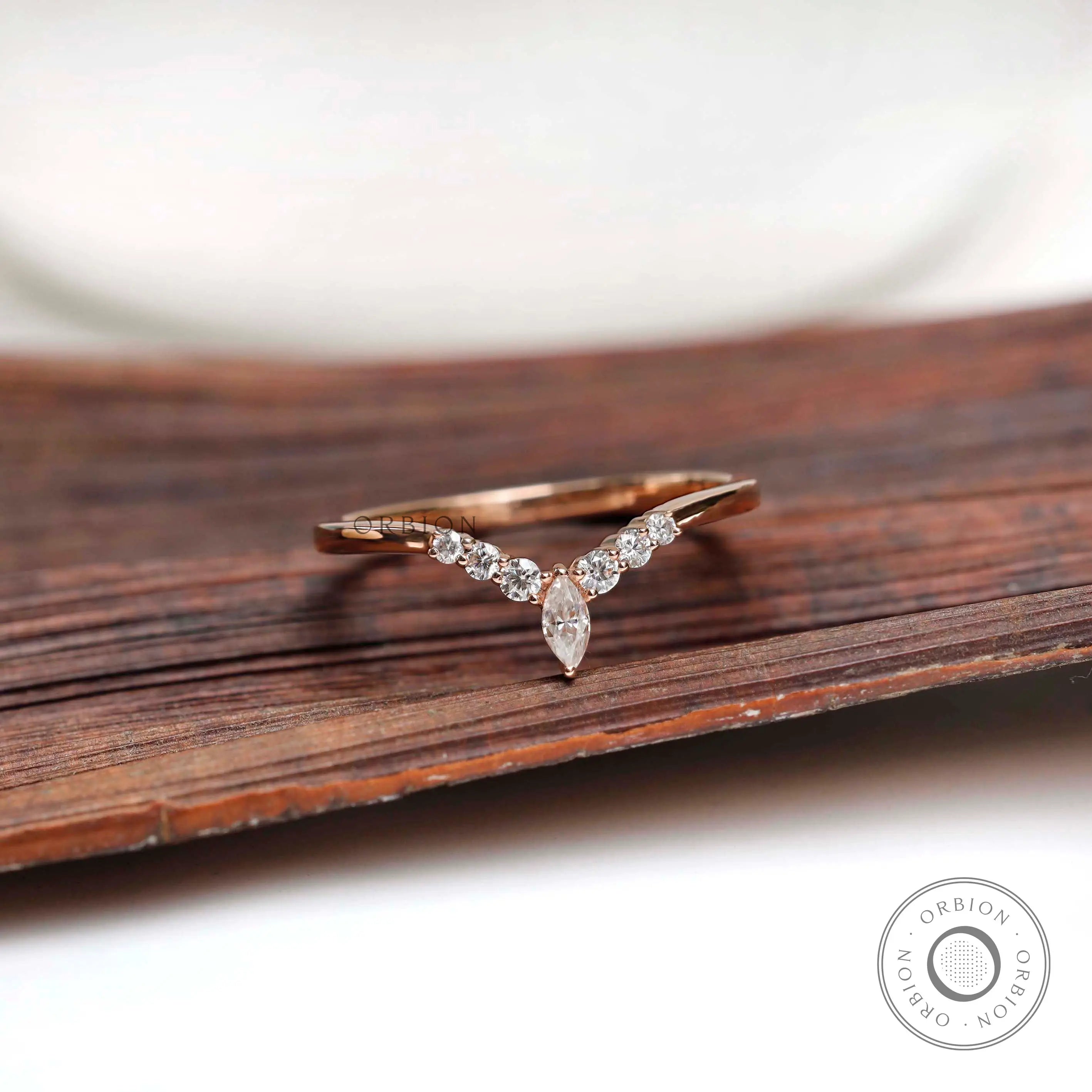 Front view of chevron moissanite wedding band on wooden surface