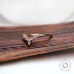 Angled top view of V-shaped wedding band with marquise center and round stones