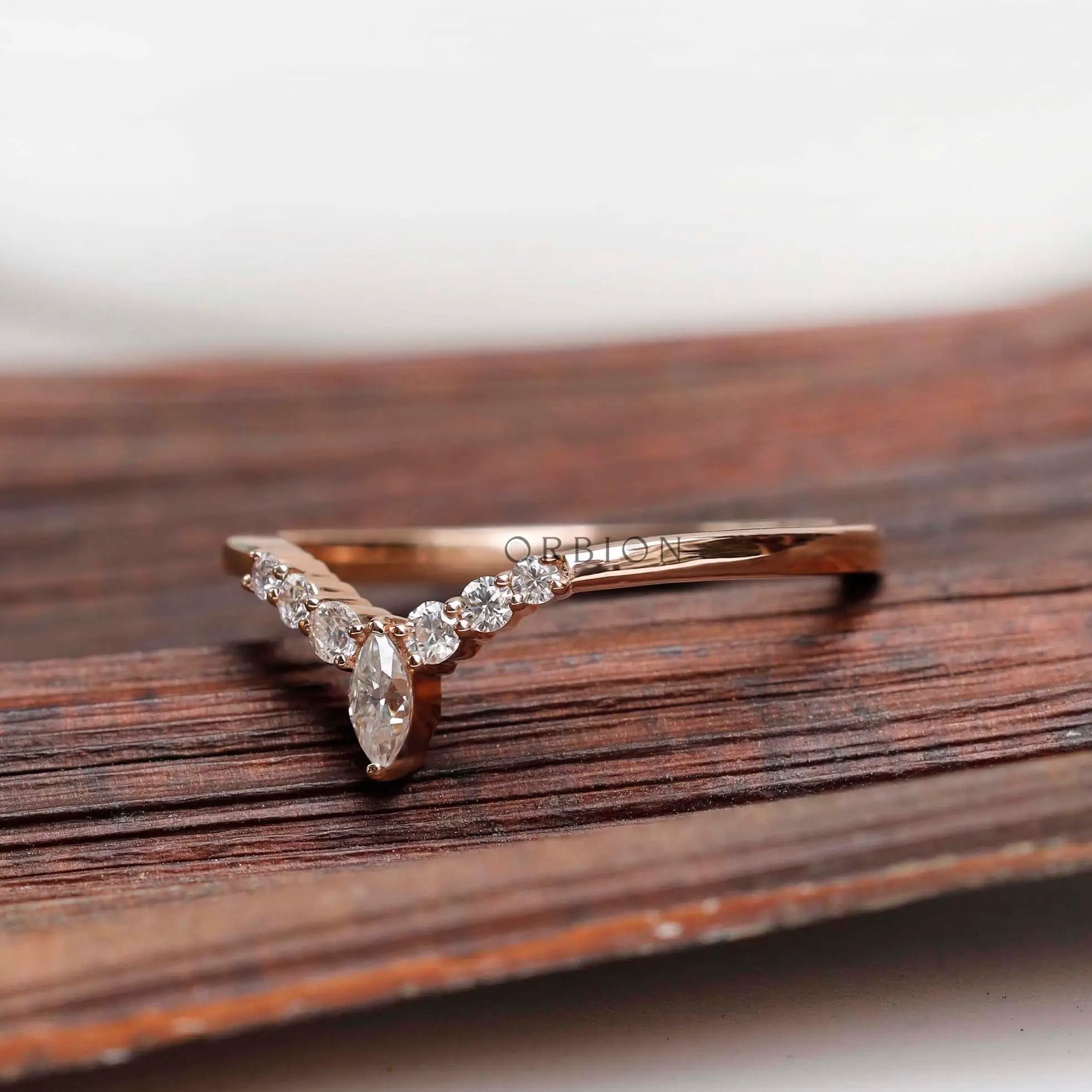Angled top view of V-shaped wedding band with marquise center and round stones