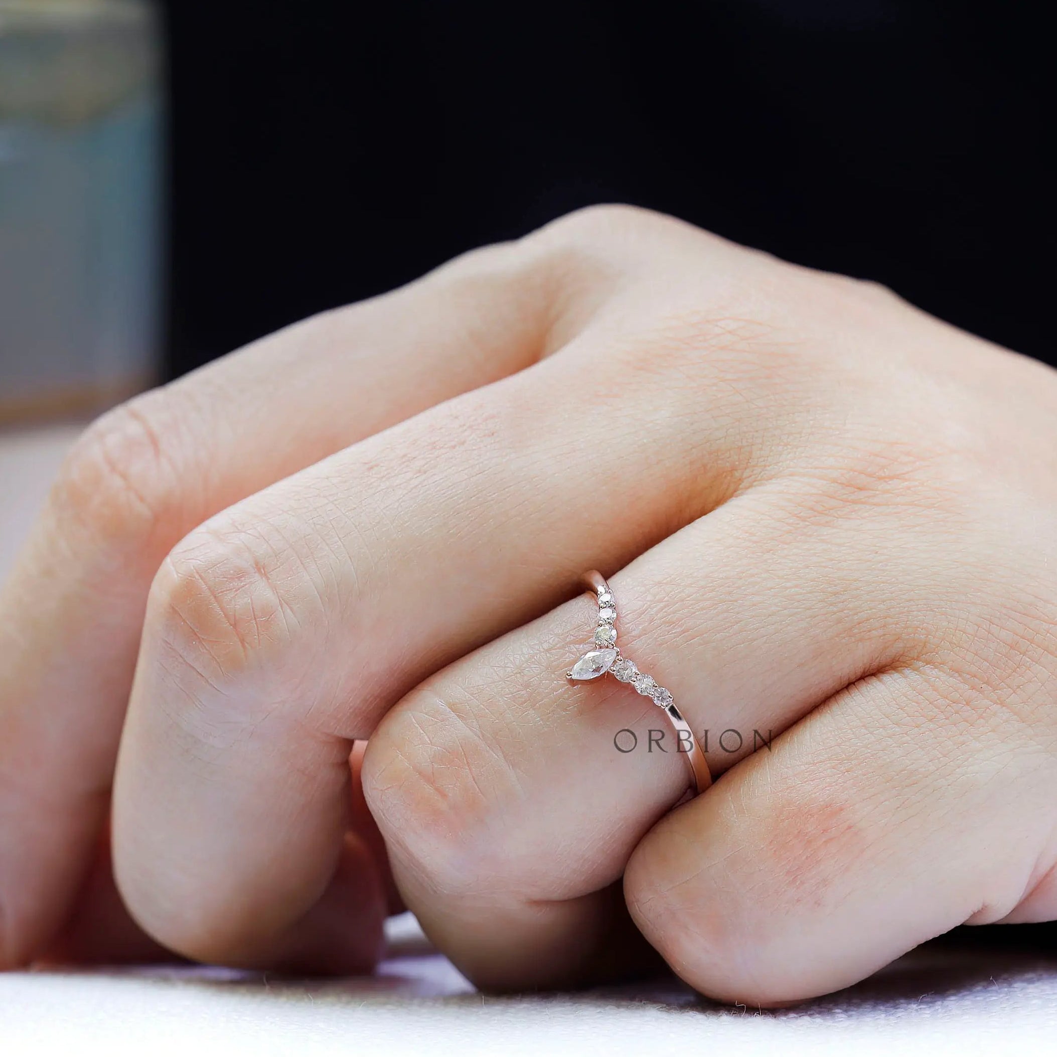 Close-up on-hand view highlighting round moissanite accents and marquise center