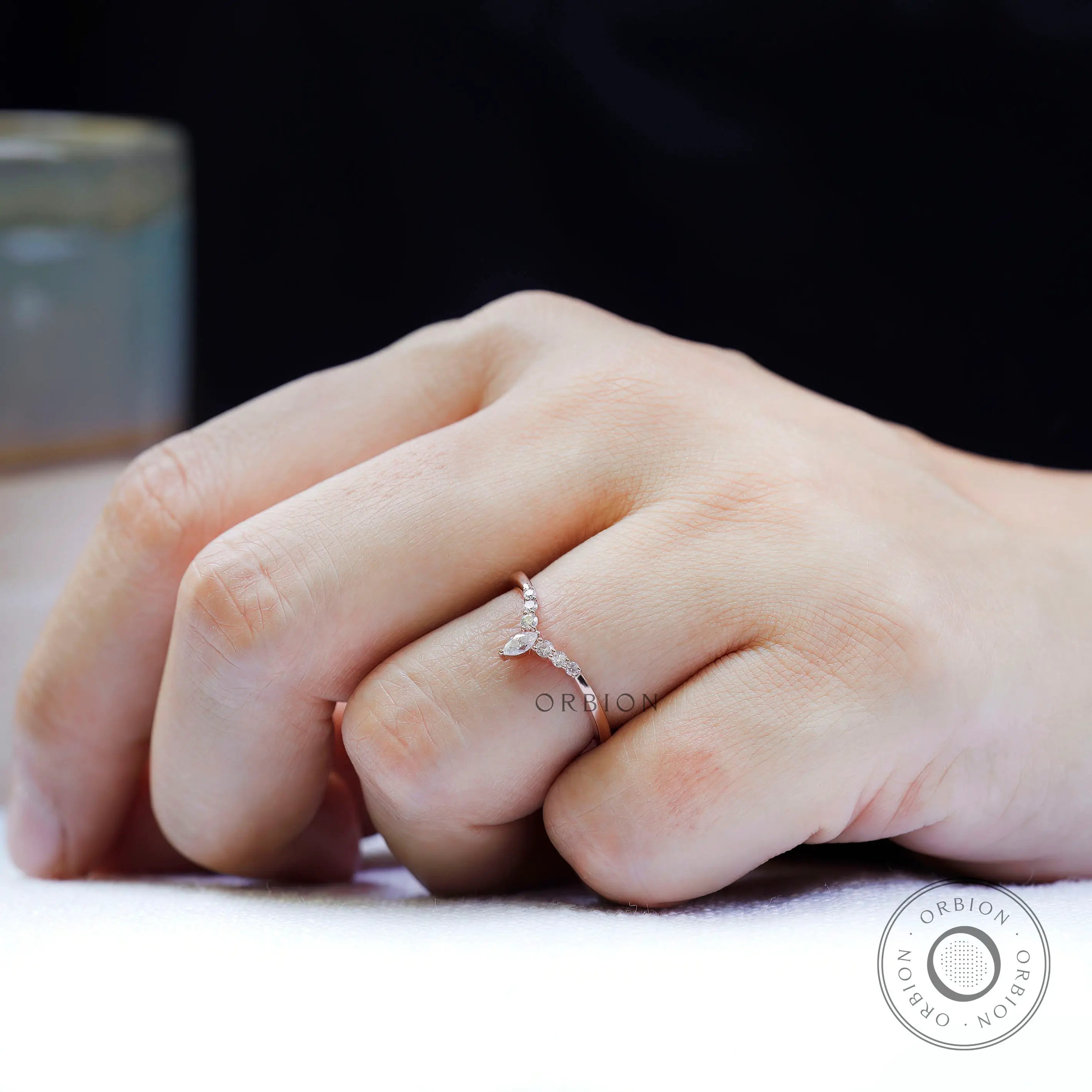 Close-up on-hand view highlighting round moissanite accents and marquise center