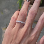 Close up view of heart cut moissanite half eternity wedding band worn on hand