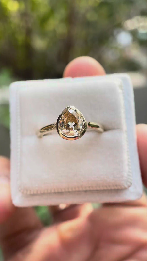 Pear Old Mine Cut light champagne moissanite bezel solitaire ring rotating view