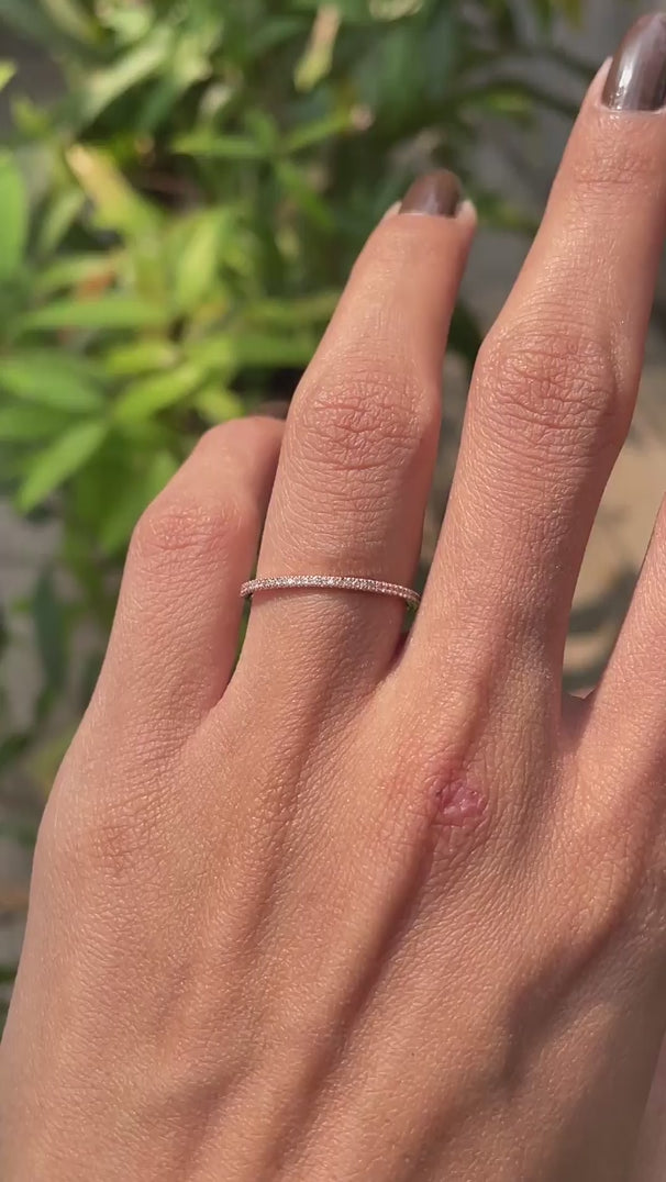 Close rotating view of slim pave moissanite wedding band in rose gold.