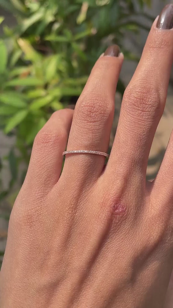 Close rotating view of slim pave moissanite wedding band in rose gold.