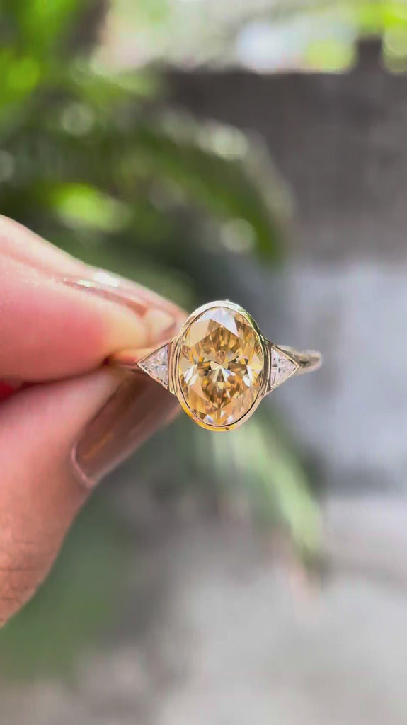 Elongated oval bezel set three stone ring in yellow gold rotating view