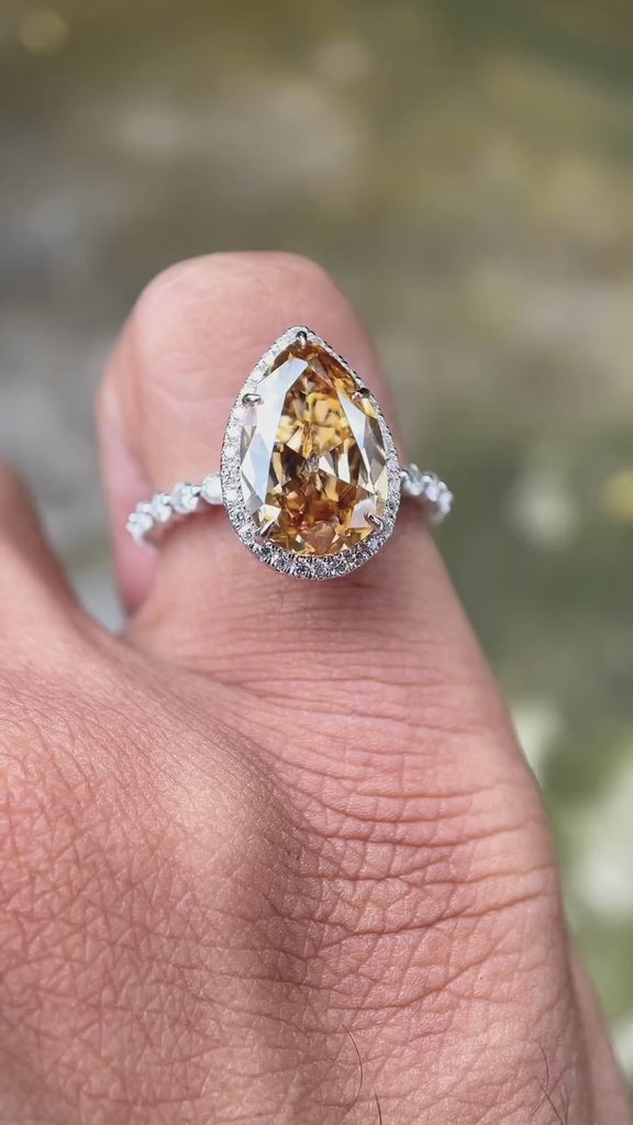 Video showcasing the pear-shaped Moissanite Old Mine Cut halo ring with round side stones in 14K white gold.