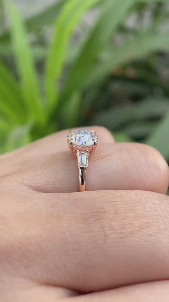 Round Old European Cut moissanite three stone ring with baguette side stones in 10K rose gold rotating view