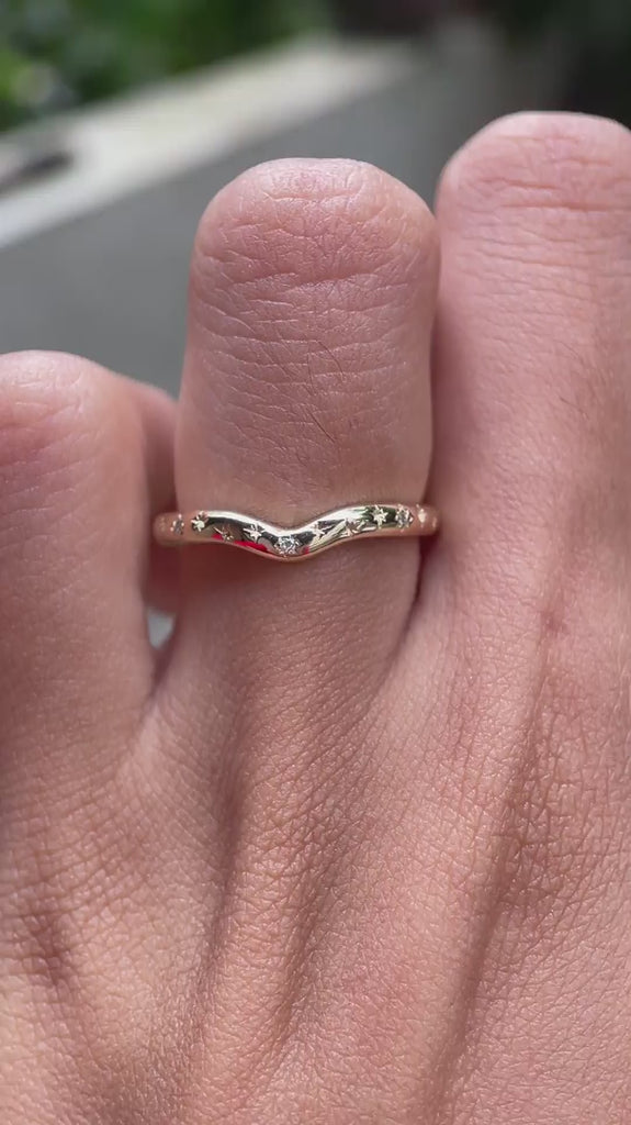 Close rotating view of curved starburst diamond ring on finger.