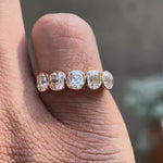 Rotating view showcasing five stone cushion moissanite bezel band worn on finger