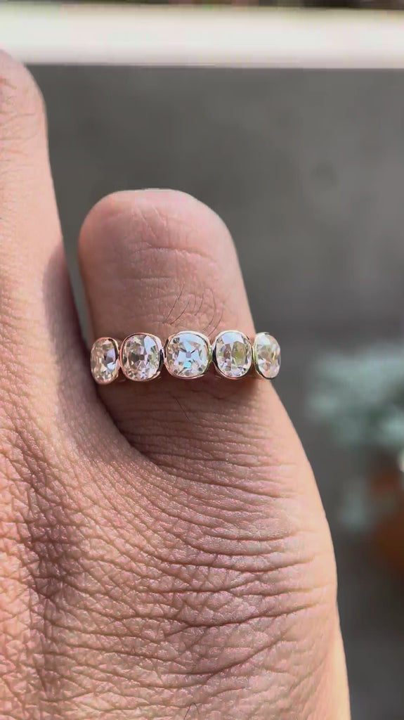 Rotating view showcasing five stone cushion moissanite bezel band worn on finger