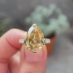 Hand worn pear Old Mine cut light champagne moissanite ring showing sparkle, pave band detail, and side profile in natural lighting