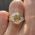 Emerald step cut light champagne moissanite bezel set three stone ring rotating view