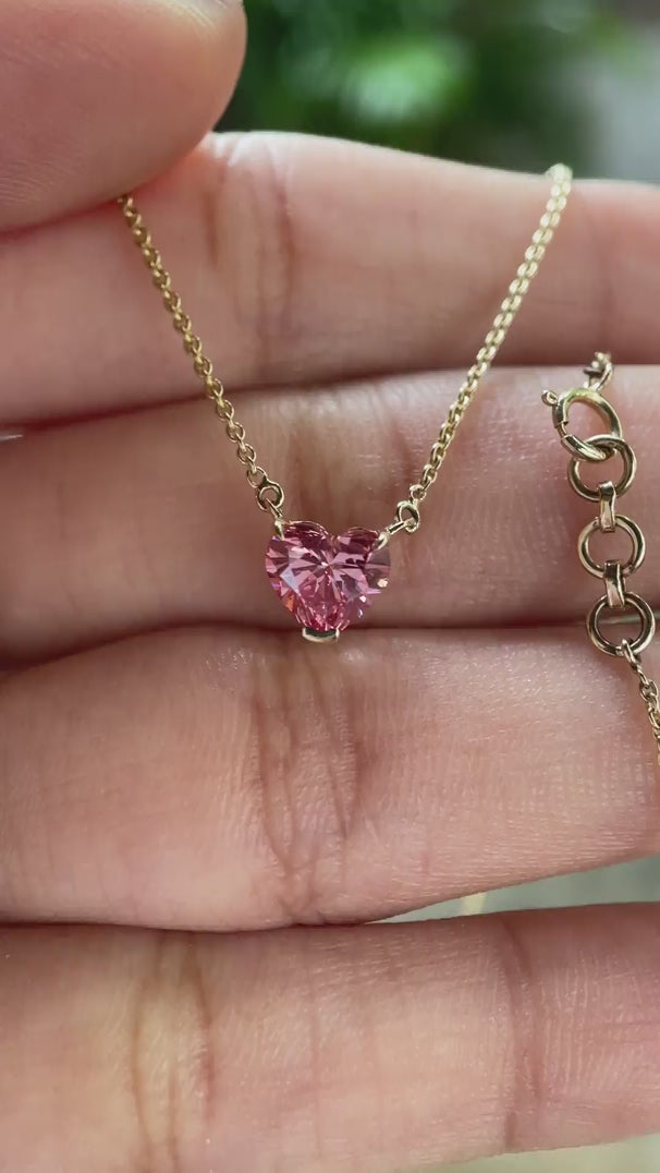 Video view of pink heart diamond pendant on chain sparkling in hand