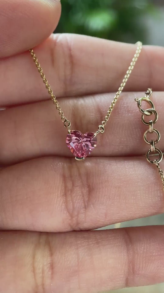 Video view of pink heart diamond pendant on chain sparkling in hand