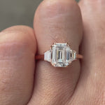 Emerald cut moissanite three stone ring rotating view highlighting trapezoid side stones and step cut brilliance