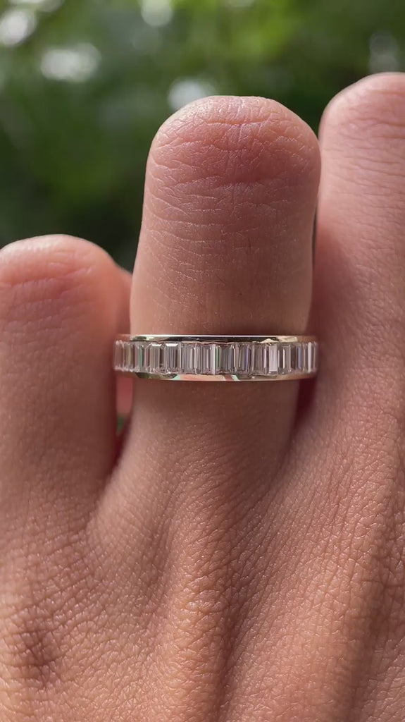 Close up view of channel set baguette moissanite eternity band worn on finger