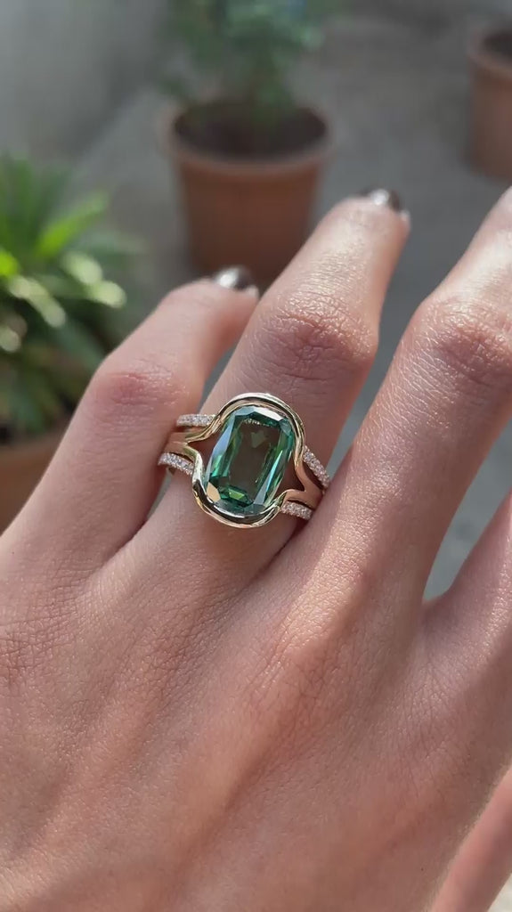 Worn on hand and rotating view of green moissanite ring set with curved bands