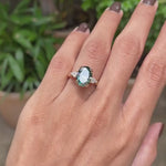 14k yellow gold cathedral ring featuring oval blue green moissanite with three stones and kite accents.