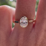 Rotating view of oval bezel set solitaire engagement ring on hand in natural light