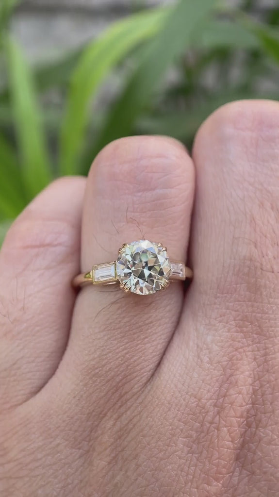 Moissanite three-stone round Old European cut engagement ring with baguette side stones, displayed in a video showcasing the ring from different angles.
