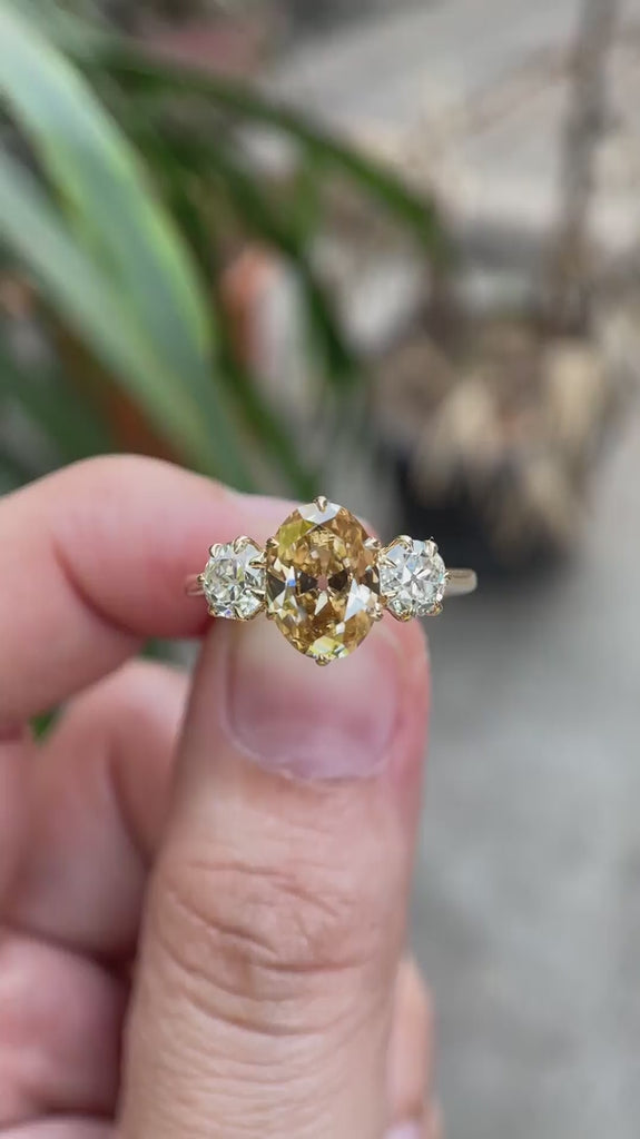 Three stone oval champagne moissanite ring rotating to show details