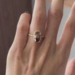 Dark champagne oval Old Mine Cut moissanite bezel set engagement ring in 14K yellow gold rotating view