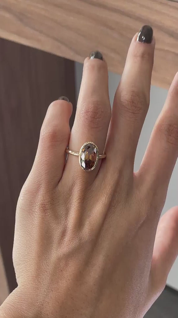 Dark champagne oval Old Mine Cut moissanite bezel set engagement ring in 14K yellow gold rotating view