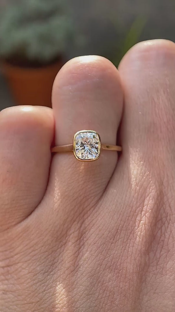 Cushion cut lab grown diamond bezel solitaire ring in 14K yellow gold rotating view