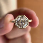 Moissanite octagon step cut bezel set cathedral style solitaire ring in 10K yellow gold