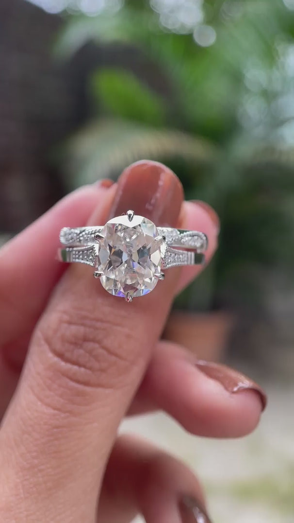 Moissanite engagement ring featuring an elongated cushion center stone with side stones, displayed in a detailed video