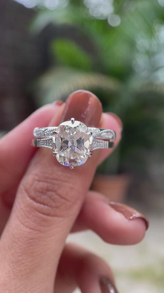 Moissanite engagement ring featuring an elongated cushion center stone with side stones, displayed in a detailed video