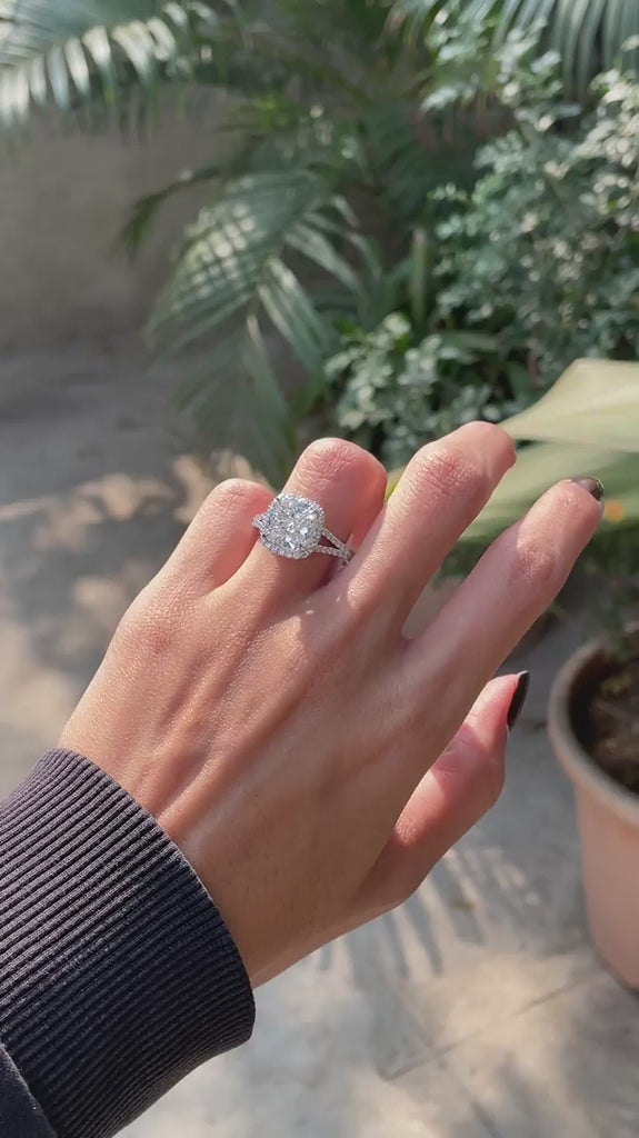 cushion halo engagement ring with round diamond accents on finger video 