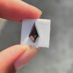 Kite step cut black moissanite rotating to showcase sharp facets and deep reflective surface