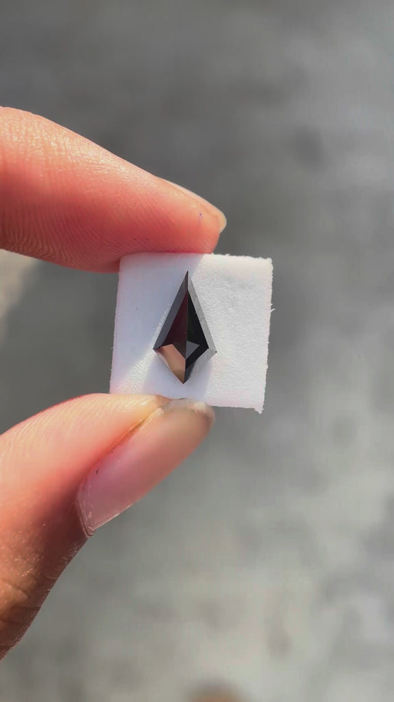 Kite step cut black moissanite rotating to showcase sharp facets and deep reflective surface