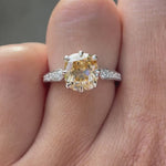 Moissanite engagement ring with an elongated cushion cut center stone, showcasing round brilliant cut side stones in a 18K yellow gold setting.