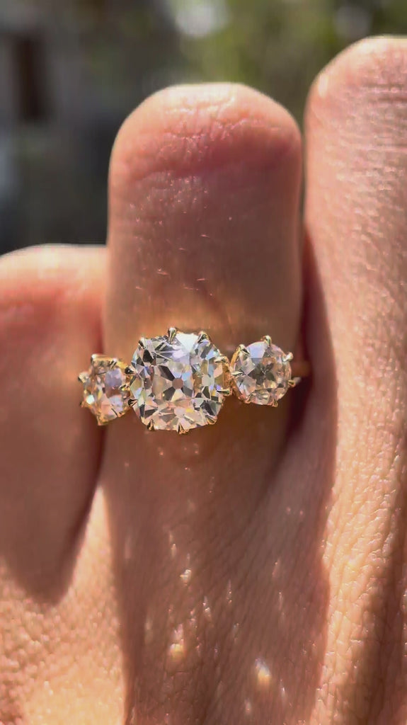 Rotating video showcasing vintage three-stone ring worn on finger in yellow gold.