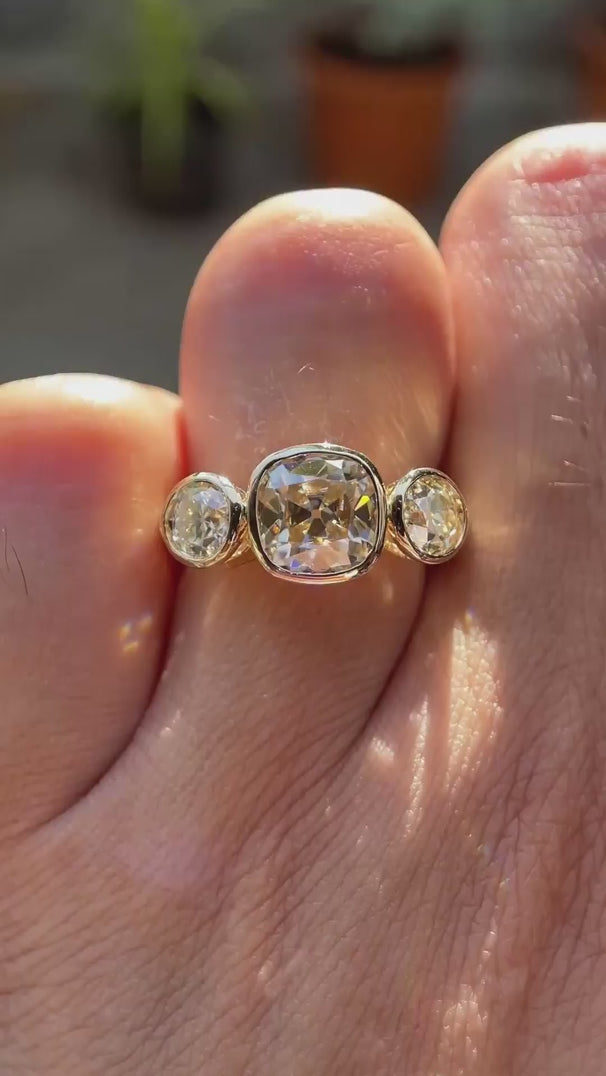 Three stone Old Mine cushion champagne moissanite ring in 10K yellow gold rotating view