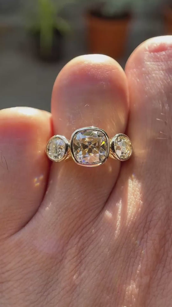 Three stone Old Mine cushion champagne moissanite ring in 10K yellow gold rotating view