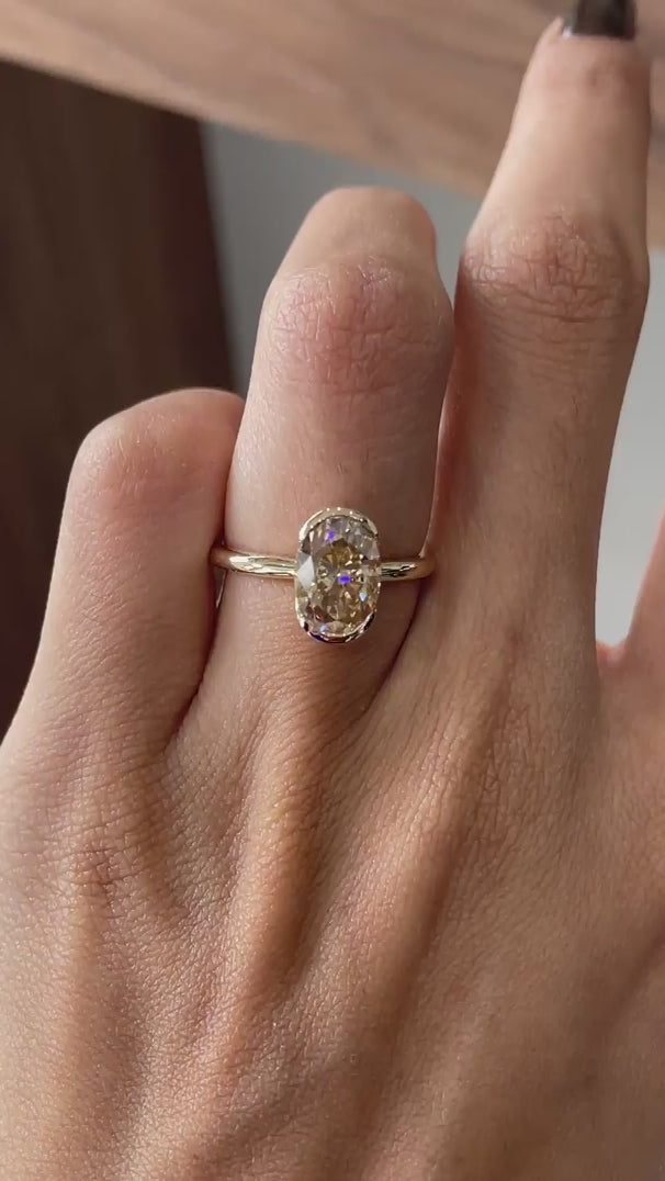 Video shows an oval dark champagne half bezel floating ring rotating view.