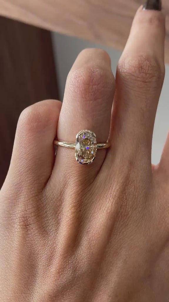 Video shows an oval dark champagne half bezel floating ring rotating view.