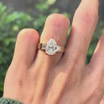 Rotating lifestyle video of pear lab diamond engagement ring on hand.