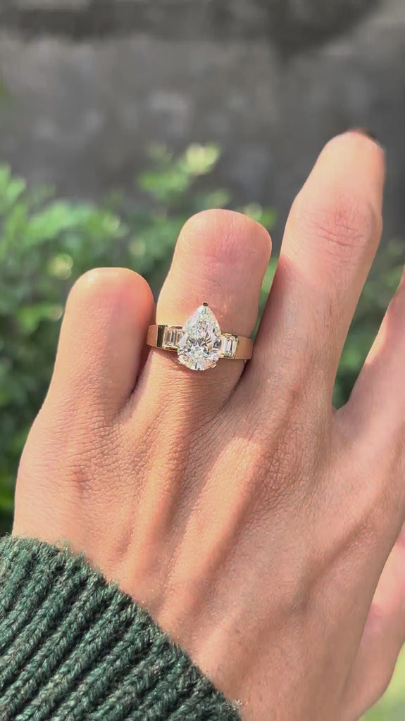 Rotating lifestyle video of pear lab diamond engagement ring on hand.