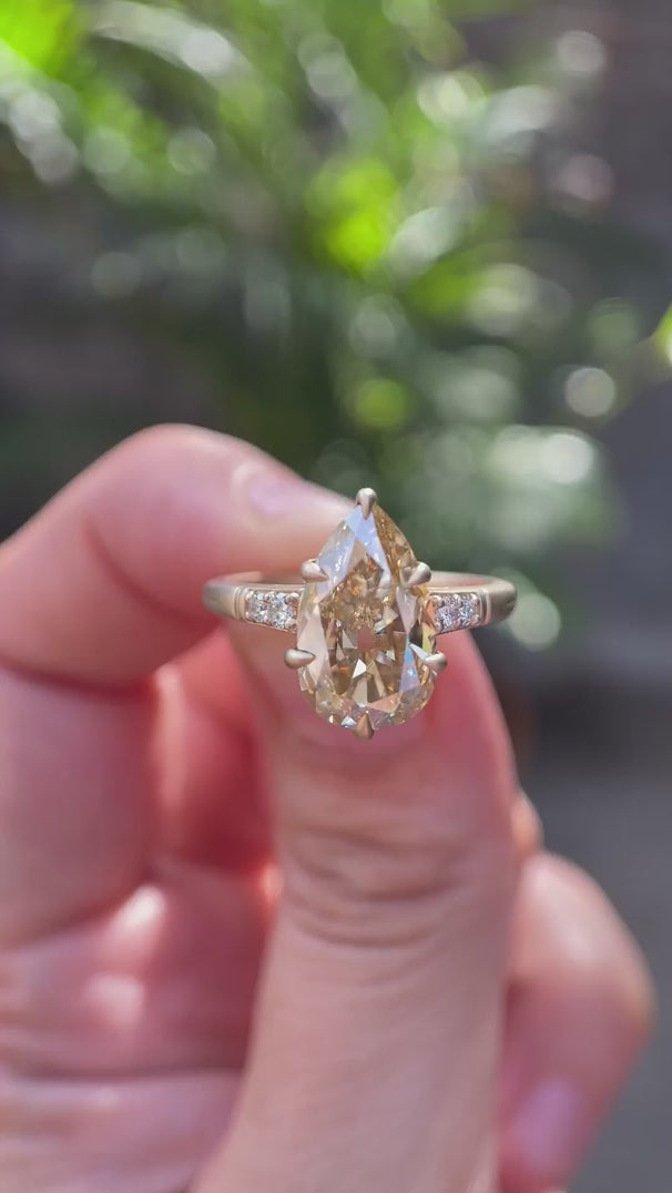 Pear cut light champagne moissanite ring shown from multiple angles in 10K yellow gold